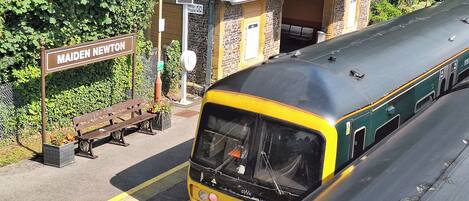 A train station platform with a bench and a sign reading "Maiden Newton".