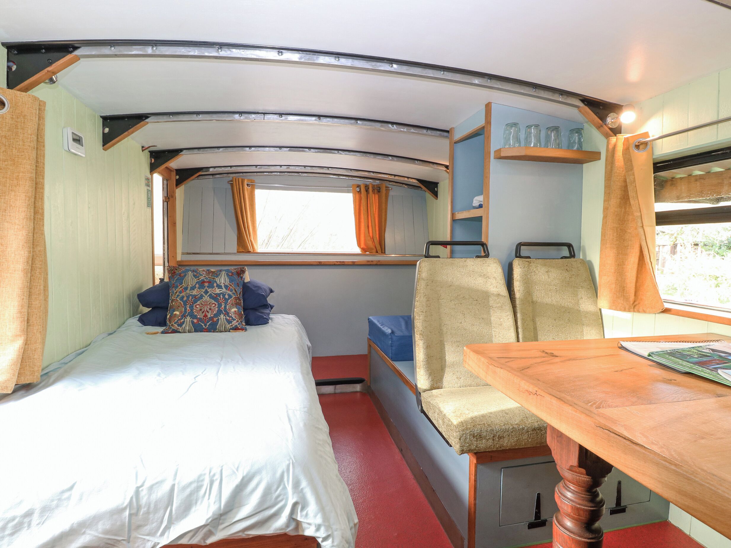 A compact, well-lit room with a bed, two chairs, a small table, and a window with curtains.