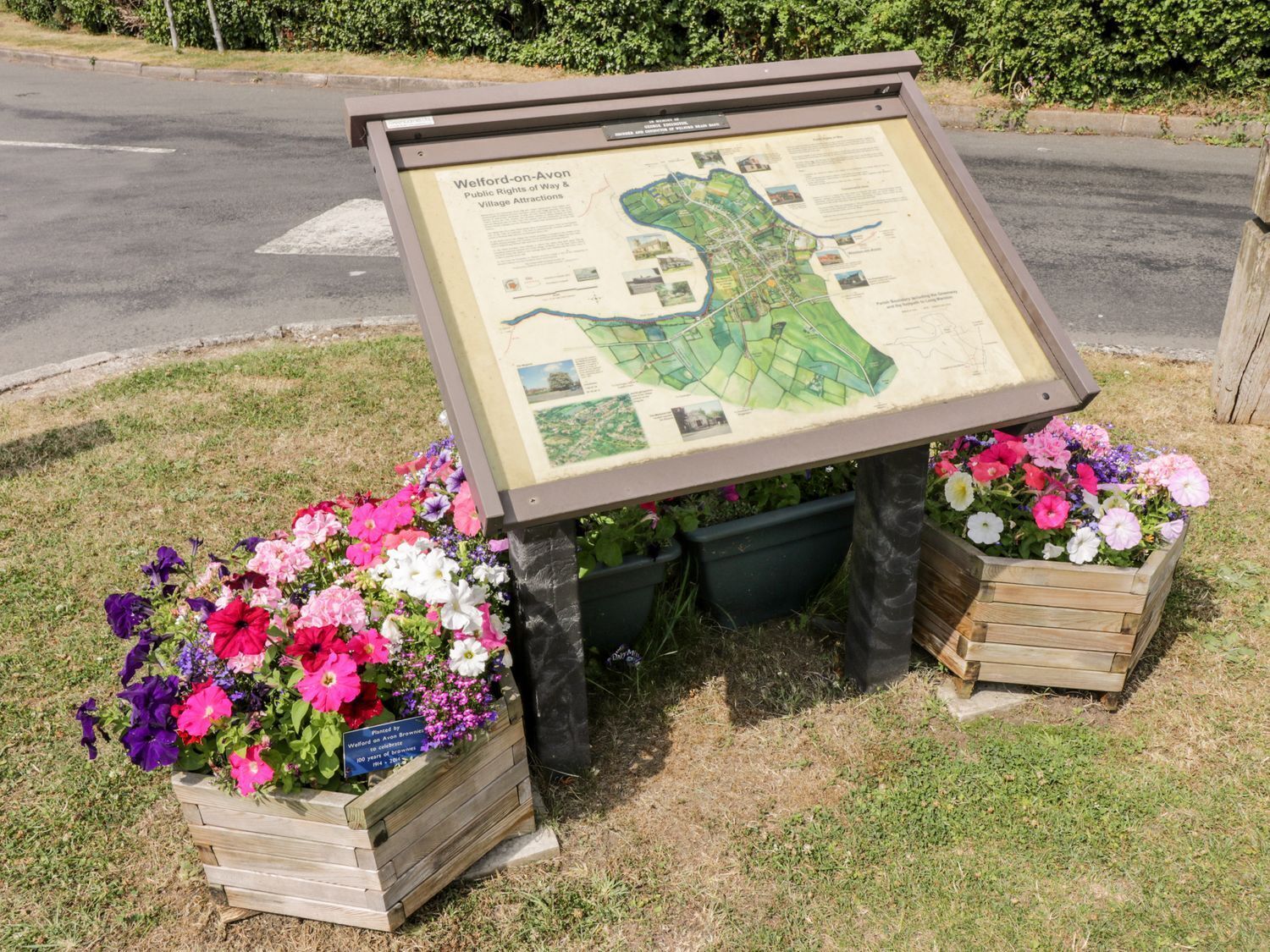 A historical marker with a map and information about Wegford-on-Avon, surrounded by flower planters.