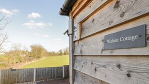 Pared exterior de madera con un letrero que dice 'Walnut Cottage'.