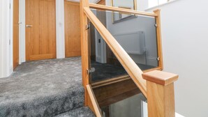 Una escalera de madera con barandillas de vidrio que conduce a una plataforma.