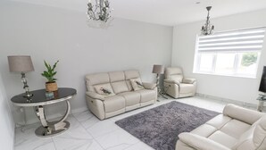 Una sala de estar moderna con un sofá, sillones, una mesa de centro y un televisor.