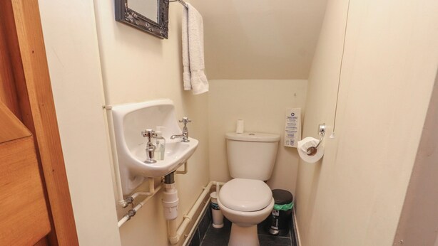 Ein kleines, kompaktes Badezimmer mit einem weißen Waschbecken, einer Toilette und einem Spiegel.