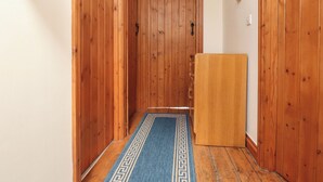 A narrow hallway with wooden walls and a blue patterned rug. - Ty Siabod (Betws-Y-Coed)