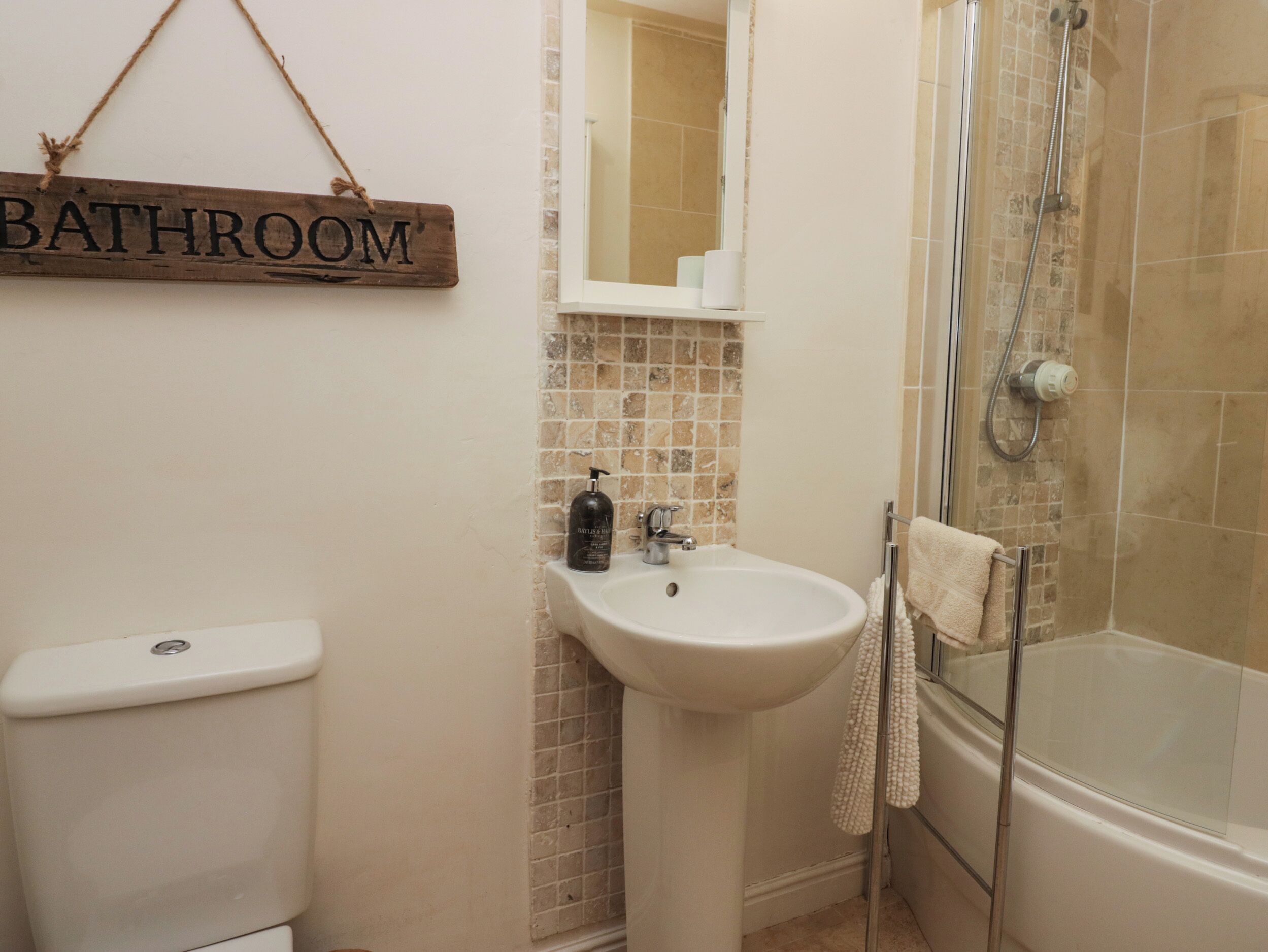 A bathroom with a toilet, sink, and glass-enclosed shower.