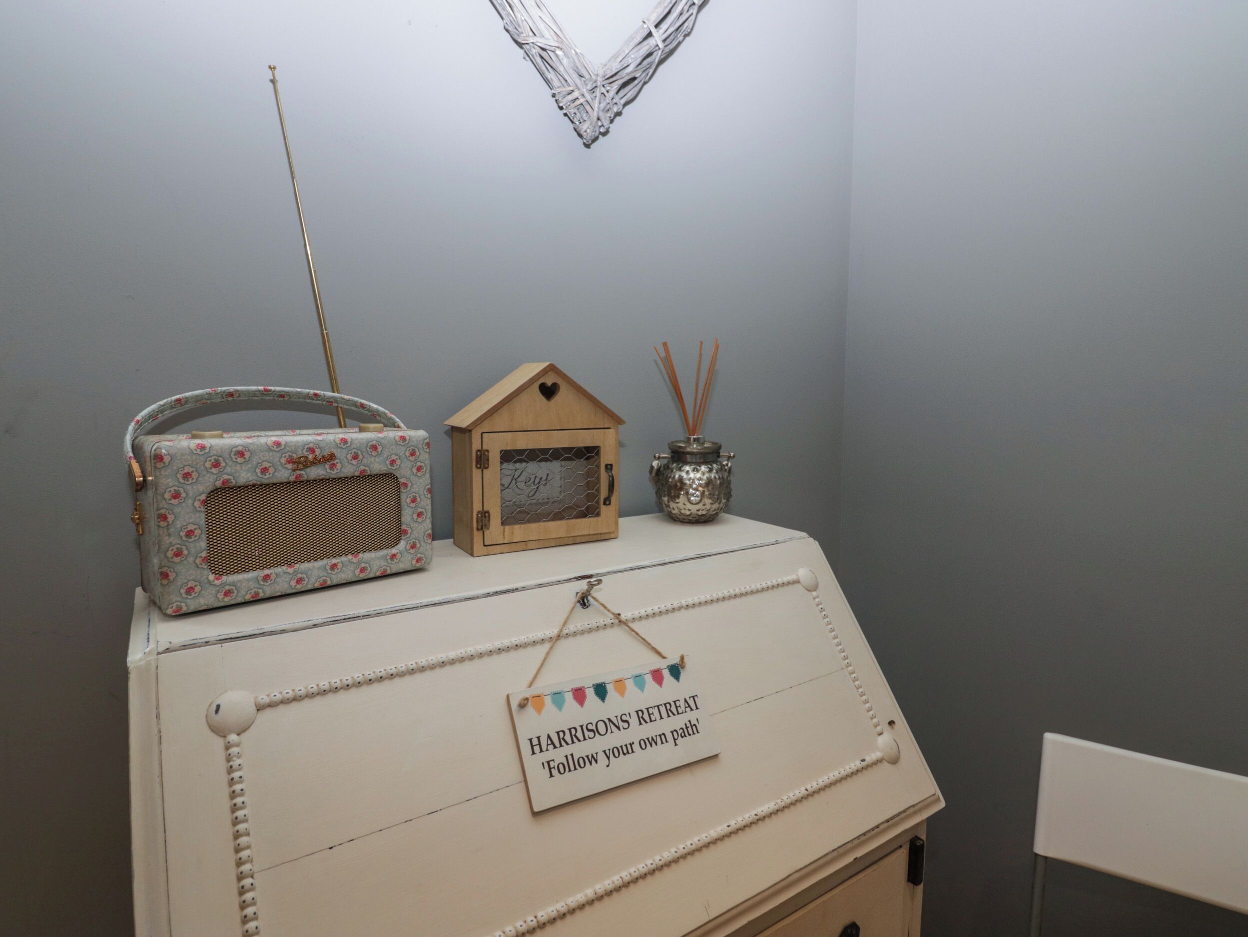 A vintage radio, a small wooden box, and a sign on a dresser.