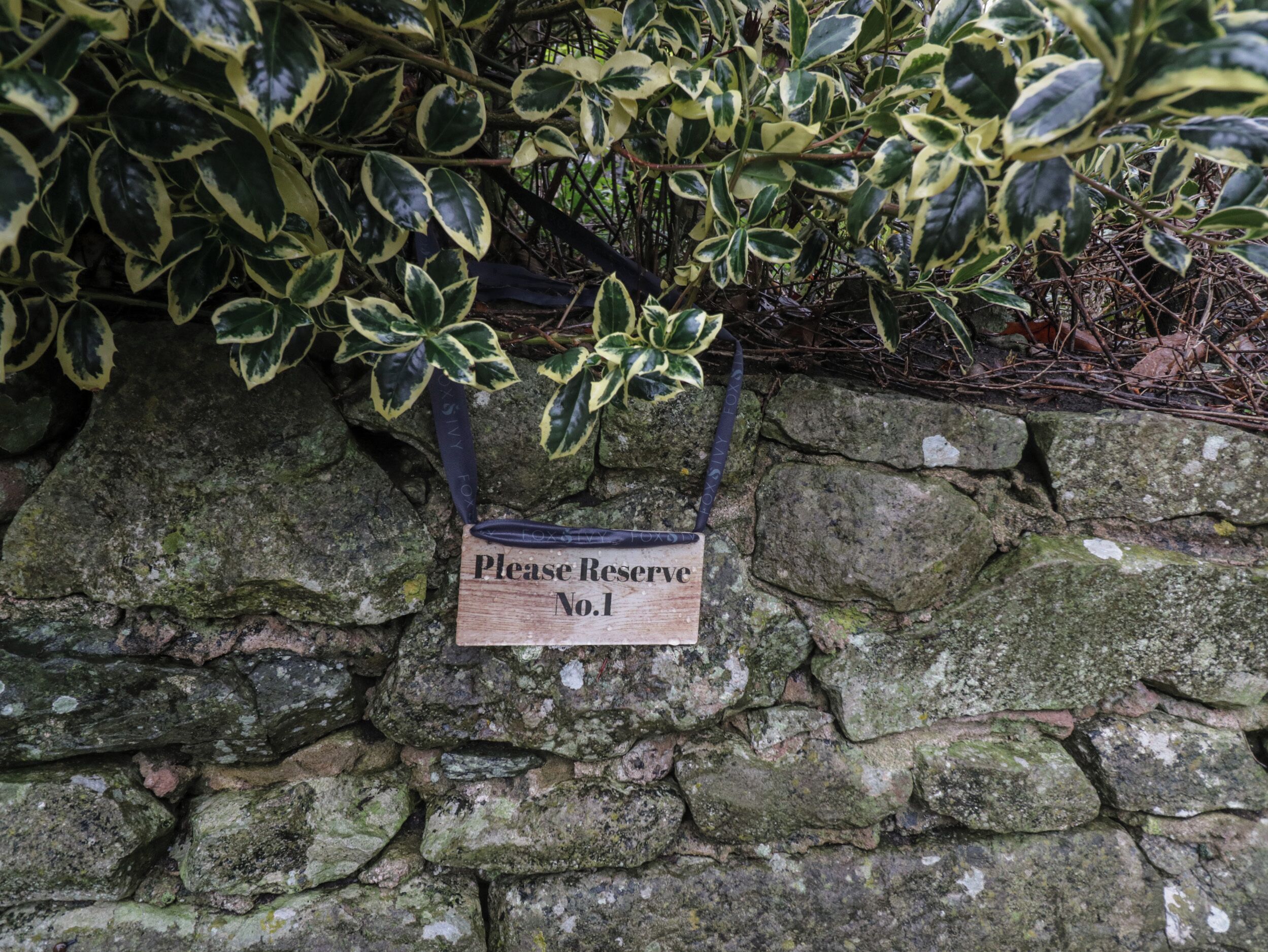 A stone wall with a sign that reads "Please Reserve No.1".