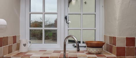 A kitchen with a sink, a window, and a bowl on the counter.