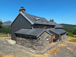 A stone building with a dark roof, a chimney, and a small window. - Ty Llugwy (Betws-Y-Coed)