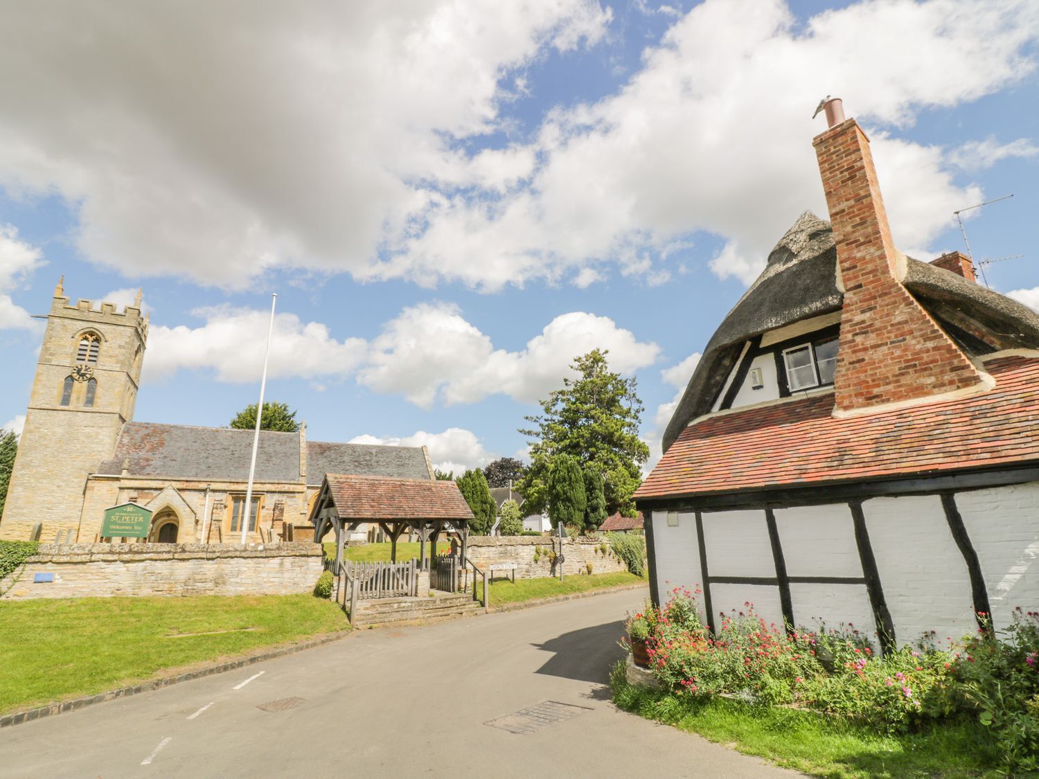 En pittoresk byväg med en kyrka och ett traditionellt hus i Tudorstil.