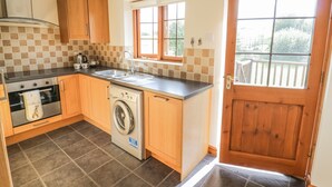 A compact kitchen with a washing machine, a stove, and a sink. - Avon View (Stratford-upon-Avon)