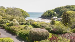 A coastal landscape with lush greenery, a paved path, and a view of the sea. - Valley View, 9 St Elmo Court (Salcombe)