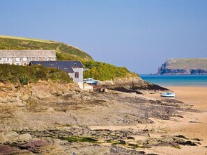 A coastal building with a beach in the background. - Sunrise Cottage (Padstow)