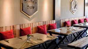A restaurant interior with wooden tables and benches, red cushions, and wall art. - Bhive Hotel (Iloilo)