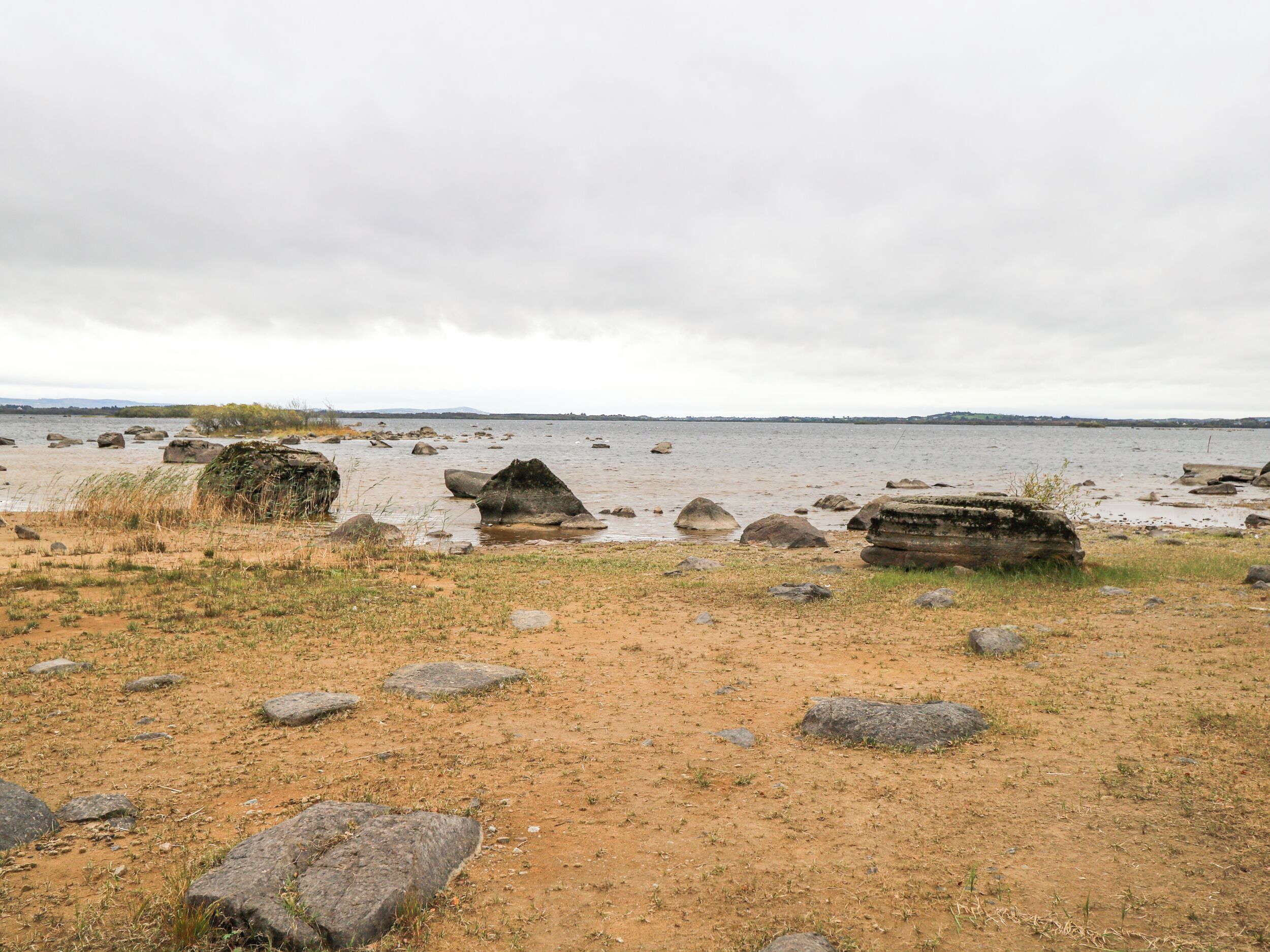 A beach with large rocks and a sandy foreground.