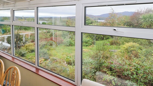 A room with large windows overlooking a garden and a lake. - Lakeview Lodge (Foxford)