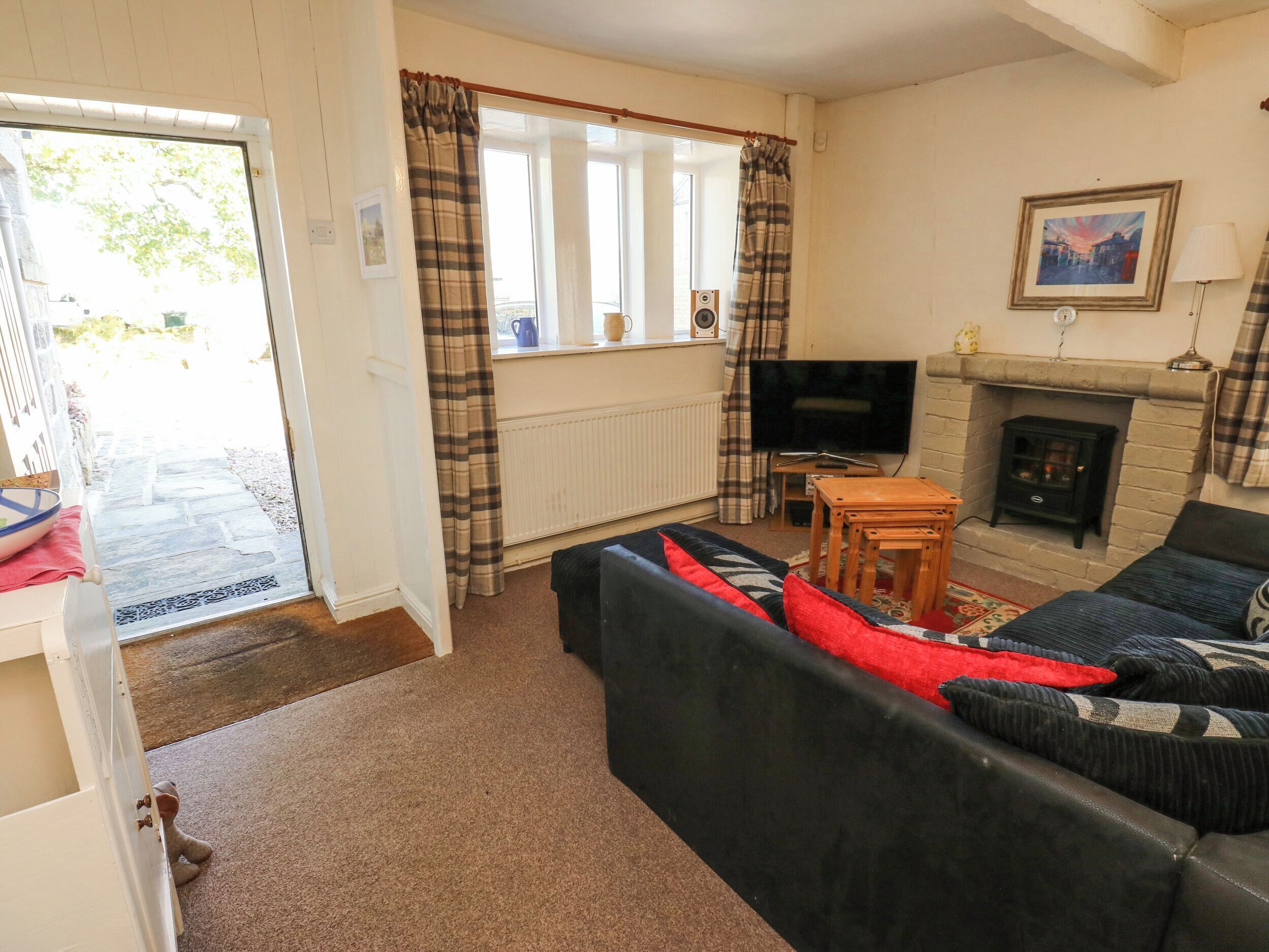 A living room with a sofa, a television, a fireplace, and a door leading to a balcony.