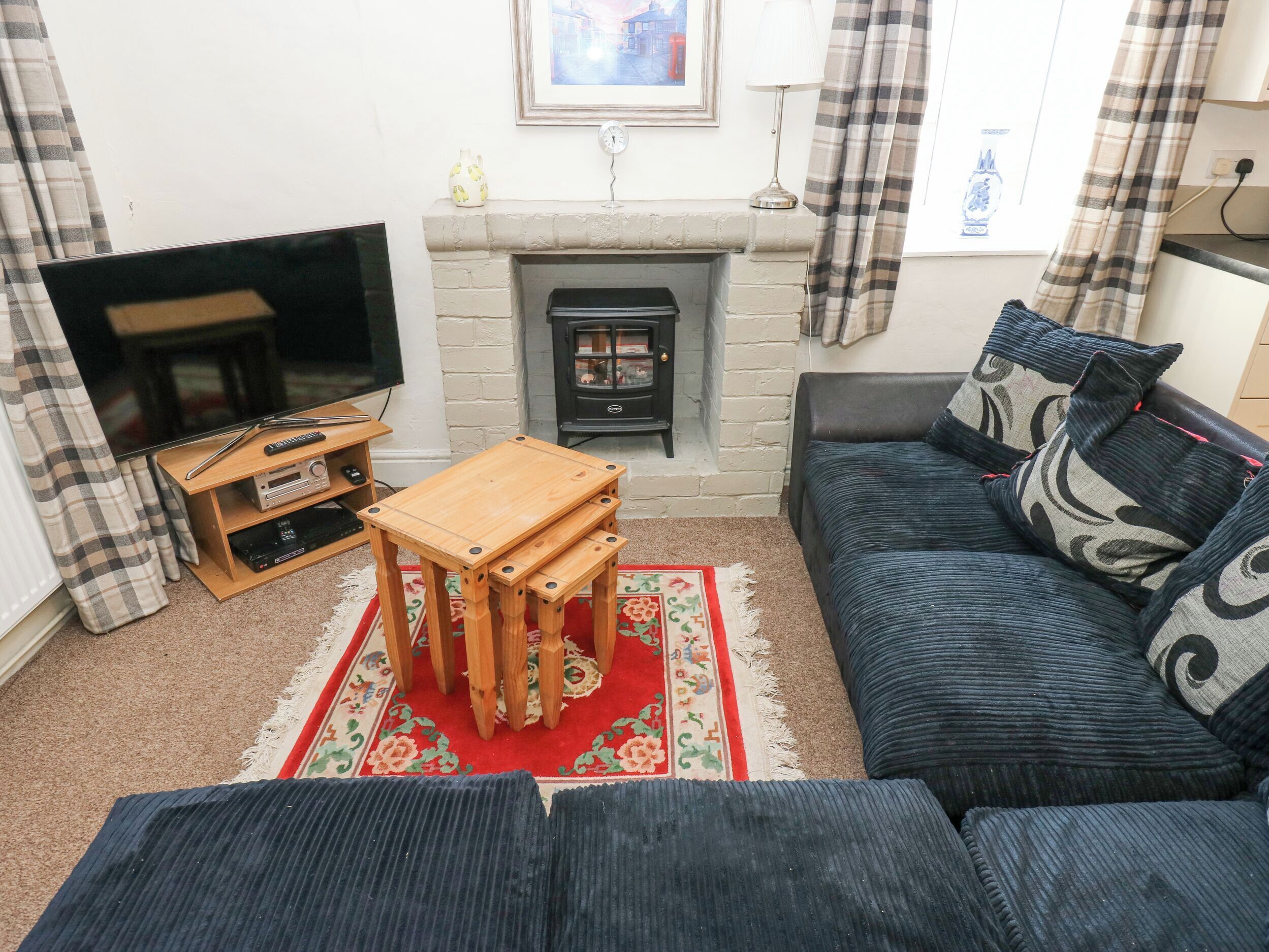 A living room with a TV, fireplace, sofa, and wooden coffee table.