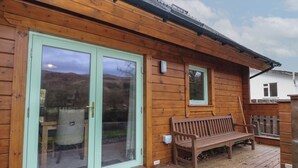 A wooden cabin with a sliding glass door, a bench, and a small window. - Bradan Lodge (Dalmally)