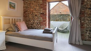 Une chambre à coucher avec un lit, une table de chevet, un tableau au mur et une vue sur l’extérieur.