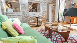 A cozy living room with a green sofa, a round coffee table, and a patterned rug. - The Stables (Penzance)