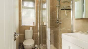 A bathroom with a toilet, a shower, and a sink.