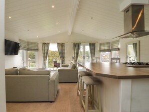 A modern kitchen with a central island, bar stools, and a dining area with a sofa and chairs.