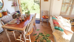 Une pièce chaleureuse avec une table à manger en bois, des chaises, un banc rembourré et une fenêtre avec des stores.