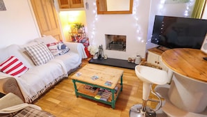 A cozy living room with a sofa, coffee table, and a fireplace. - Seaside Cottage (Cleethorpes)