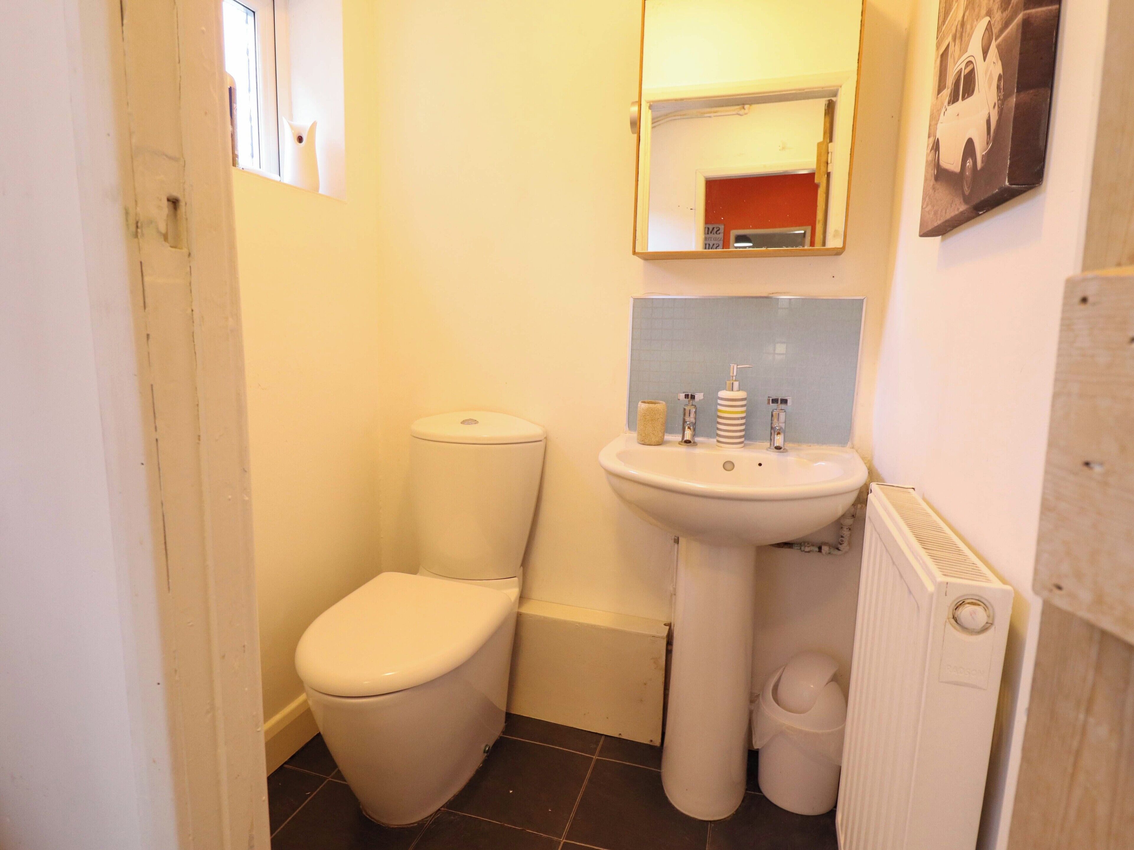 Une petite salle de bain avec des toilettes, un lavabo et un miroir.