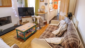A cozy living room with a television, a fireplace, a sofa, and a dining area. - Seaside Cottage (Cleethorpes)