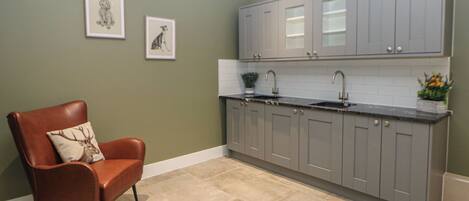 A kitchen with grey cabinets, a brown leather chair, and two framed pictures on the wall.