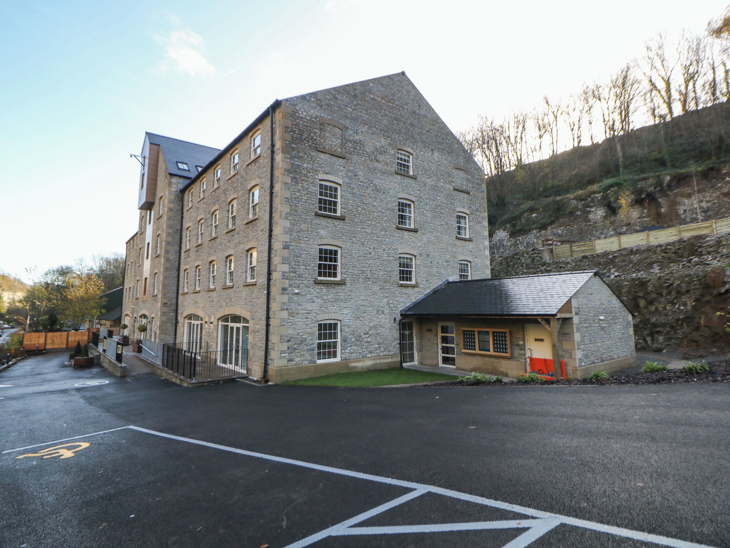 A stone building with multiple windows and a small adjacent structure.