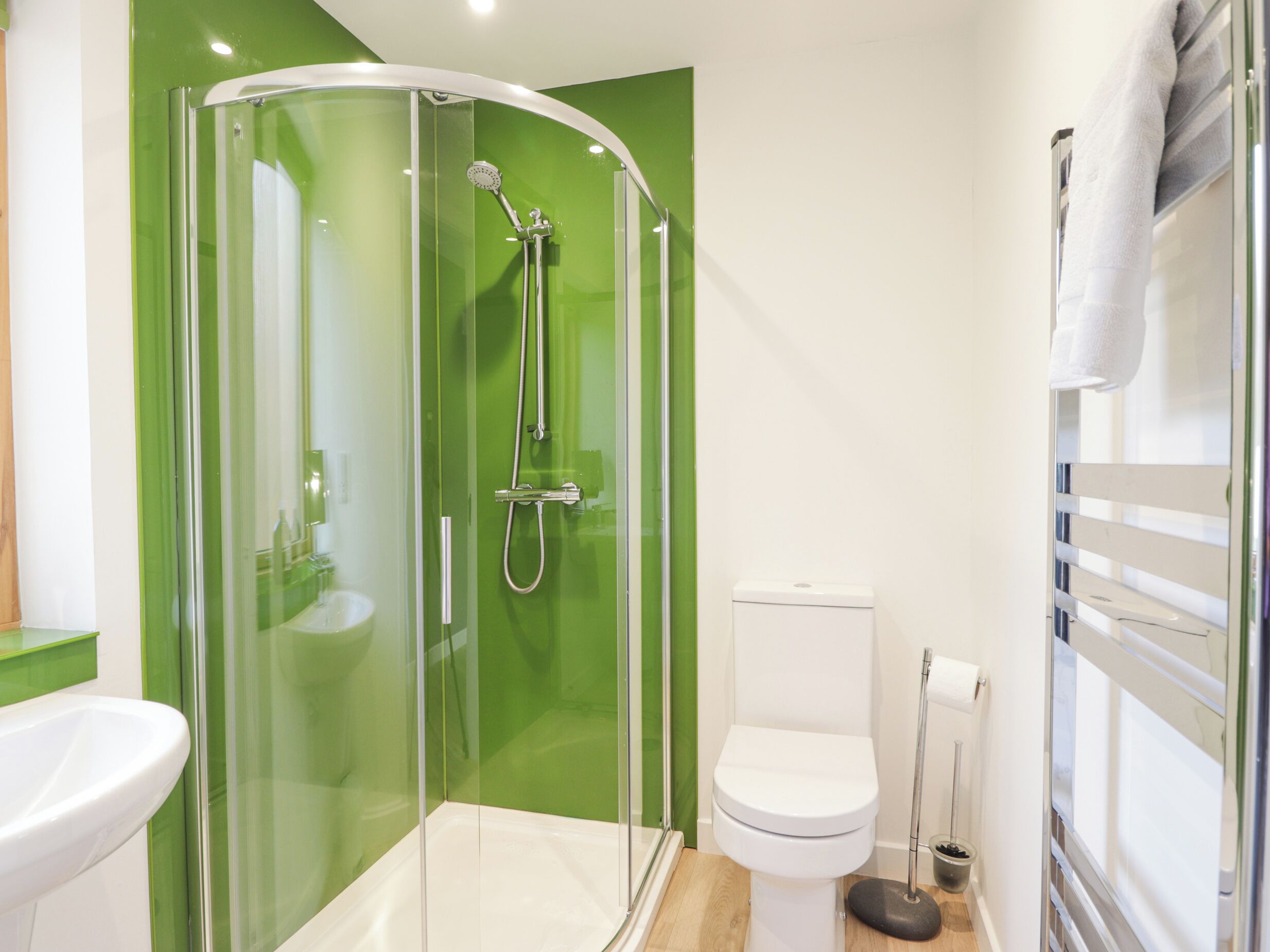 A modern bathroom with a glass-enclosed shower, a white toilet, and a sink.