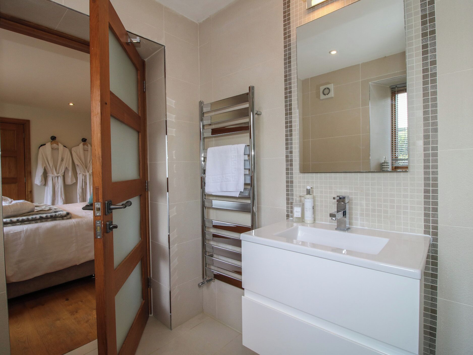 Une salle de bain avec un lavabo blanc, un porte-serviettes et un miroir.