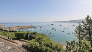 A coastal view with a marina, boats, and a clear sky. - Fronwig (New Quay)