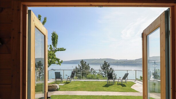A wooden-framed balcony with a view of a lake and distant hills. - Fronwig (New Quay)