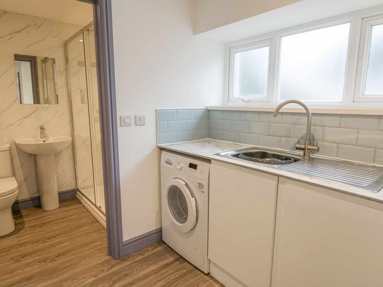 A compact bathroom with a washing machine, sink, and toilet.
