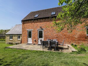 A brick house with a patio, two doors, and a small attached stone building. - Home Farm Barn (Moreton-in-Marsh)