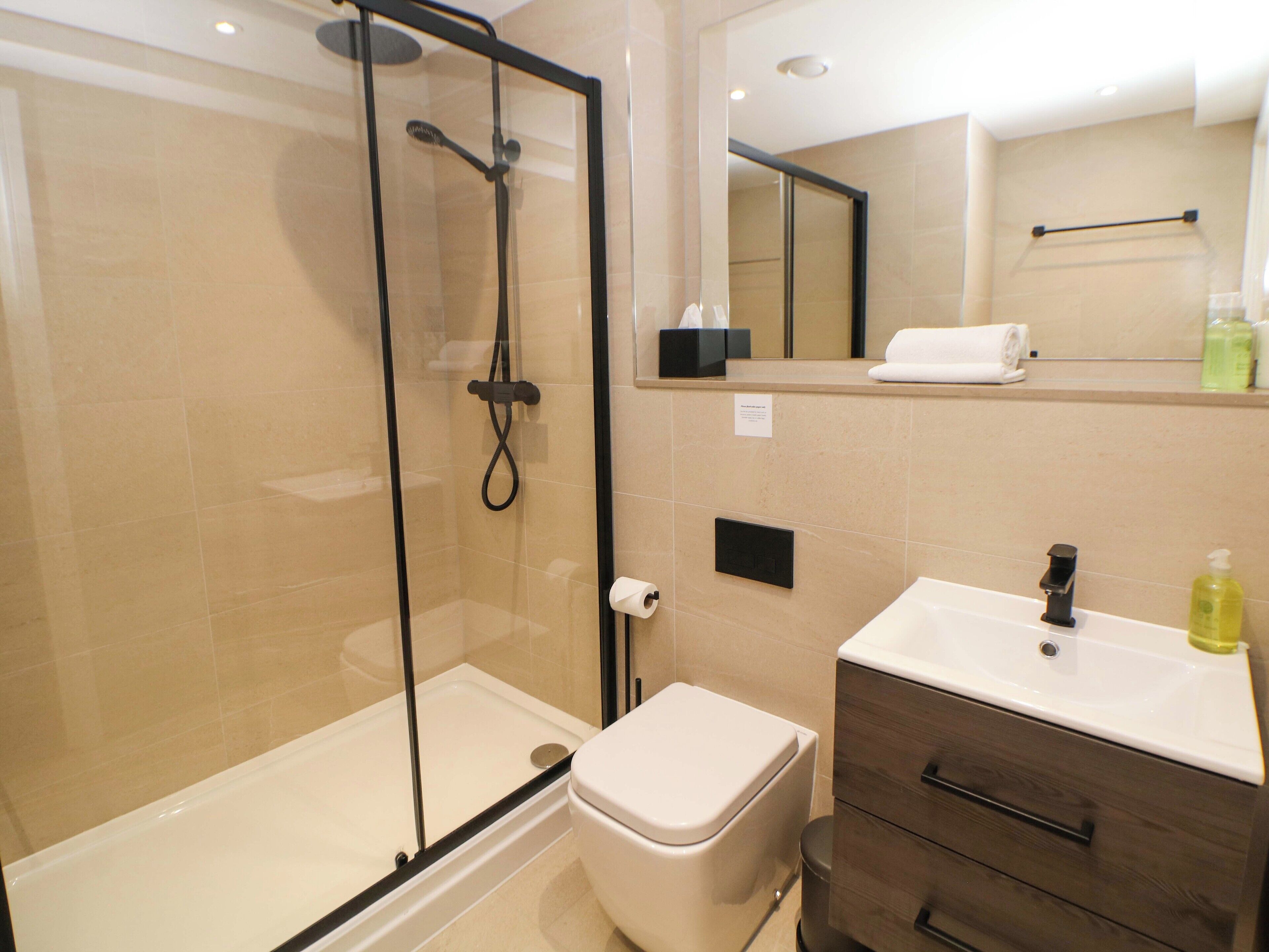 Une salle de bain moderne avec une douche à parois de verre, des toilettes et un lavabo avec un miroir au-dessus.