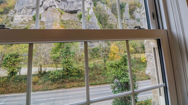 A window with a view of rocky cliffs and greenery. - 28 Rock Mill Holiday Apartments (Hope Valley)