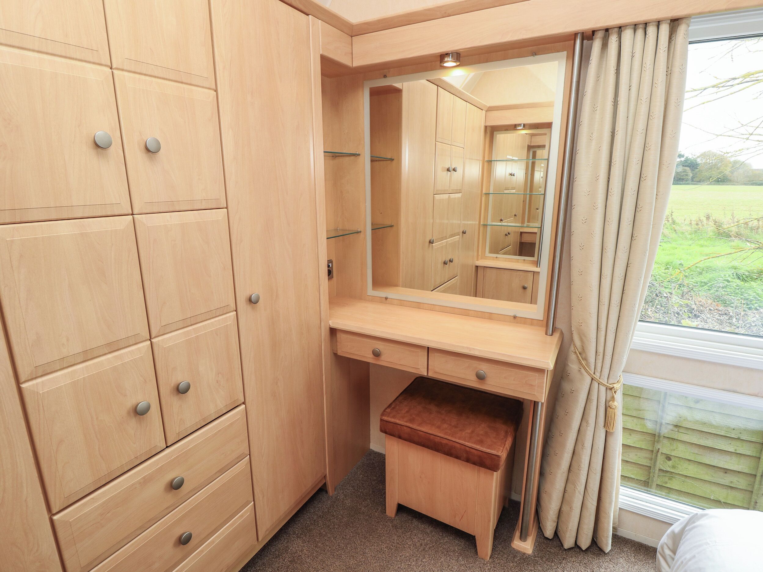 Una camera da letto compatta con un armadio in legno, uno specchio e una piccola panca.