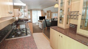 A modern kitchen with granite countertops, wooden cabinets, and a gas stove. - Seasalt Haven (Chichester)