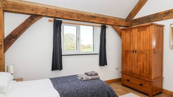 A bedroom with a bed, a wardrobe, a window with curtains, and a view of the outdoors.