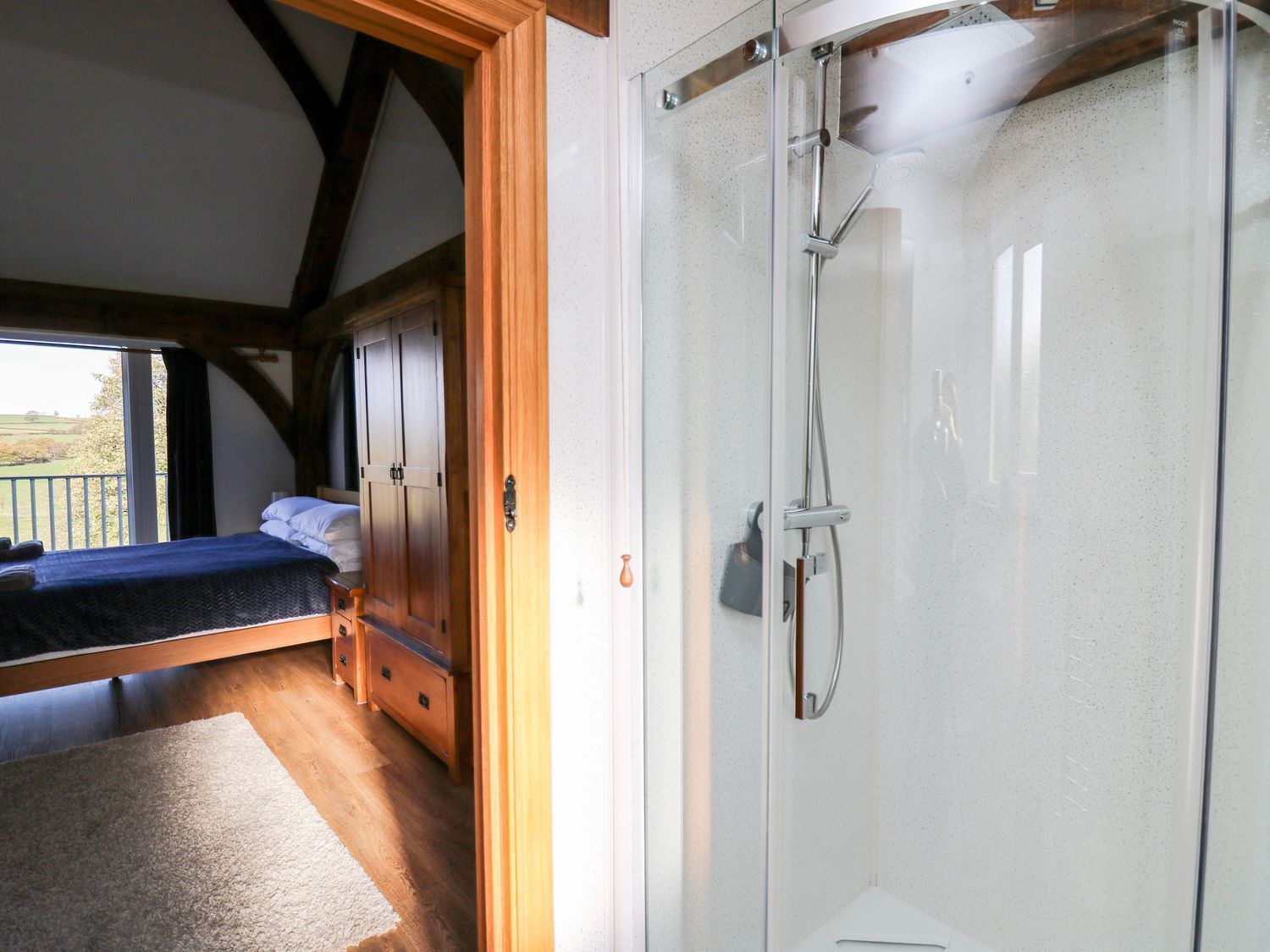 A bedroom with a bed, wooden wardrobe, and a shower enclosure.