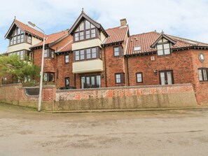 A two-story brick building with a pitched roof, large windows, and a visible garage door. - 4 Victoria Court (Sheringham)