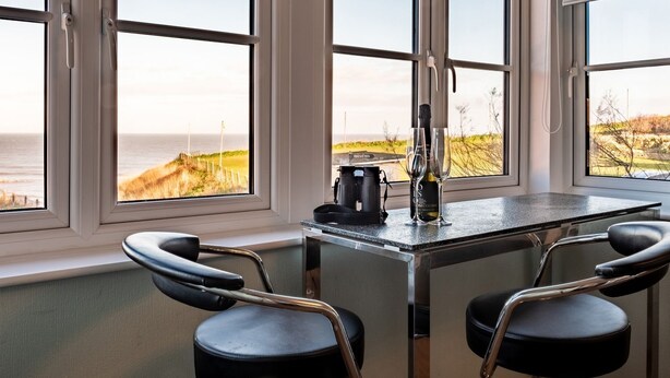 Ett kök med utsikt över havet, en kaffebryggare och två stolar.