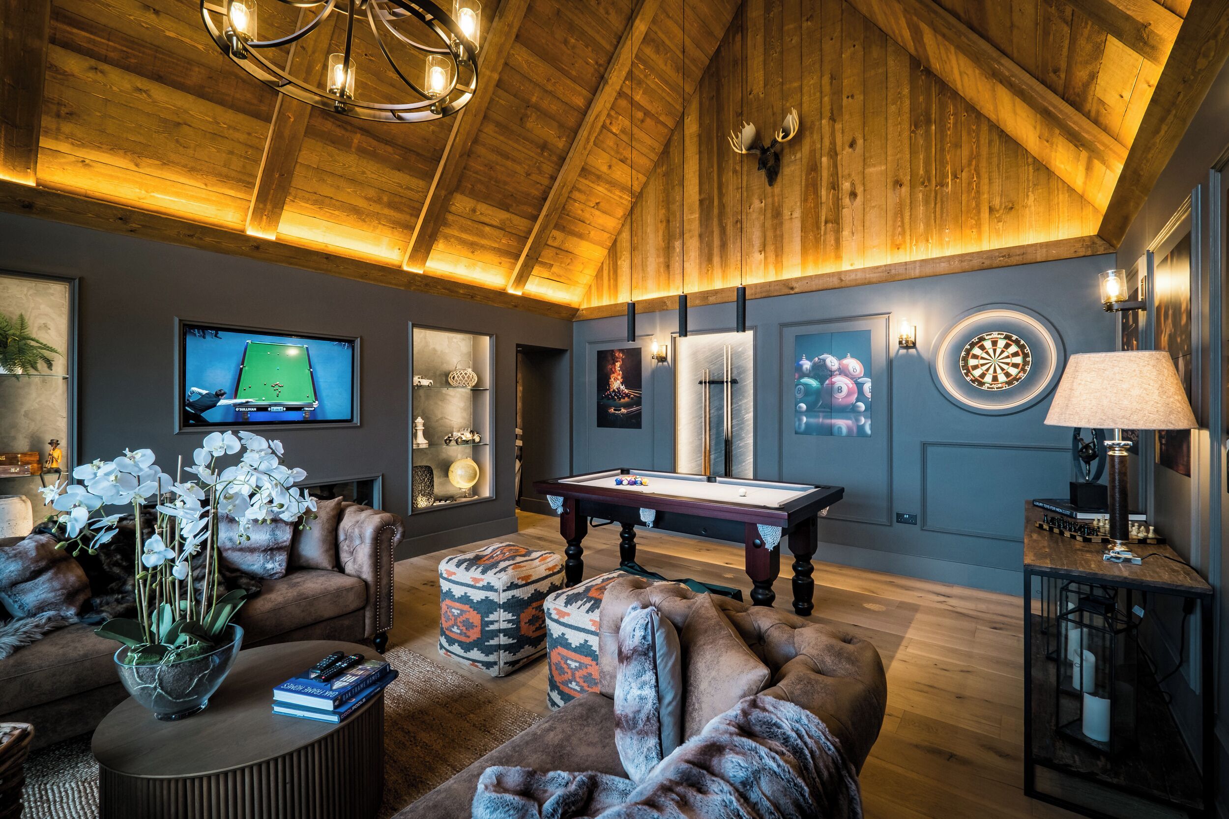 Un salon chaleureux avec une table de billard, des fauteuils confortables et un téléviseur.