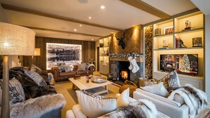 Una sala de estar acogedora con chimenea, sofás cómodos y un televisor grande montado en la pared.