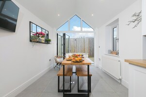 A modern kitchen with a wooden table, a white radiator, and a large window.
